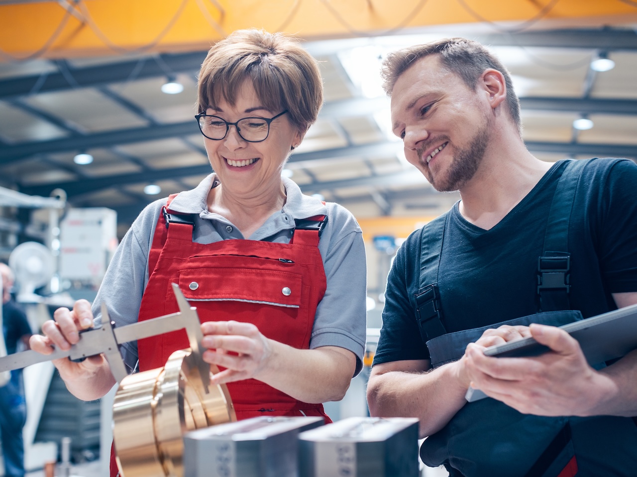 Image of two people measuring part of a pipe